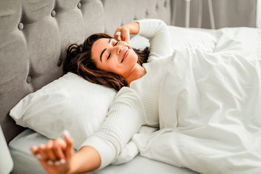 Happy young woman stretching after waking up a restful sleep.