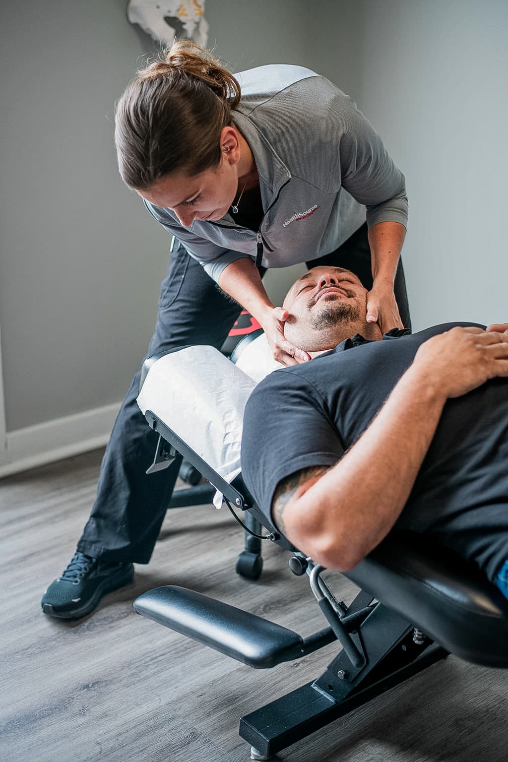 Patient lays peacefully on table as practitioner carefully adjusts their neck. 