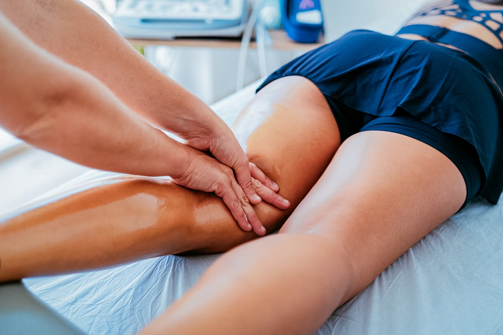 Close up of practitioner massaging the back of a patient's thigh, just above the knee. 