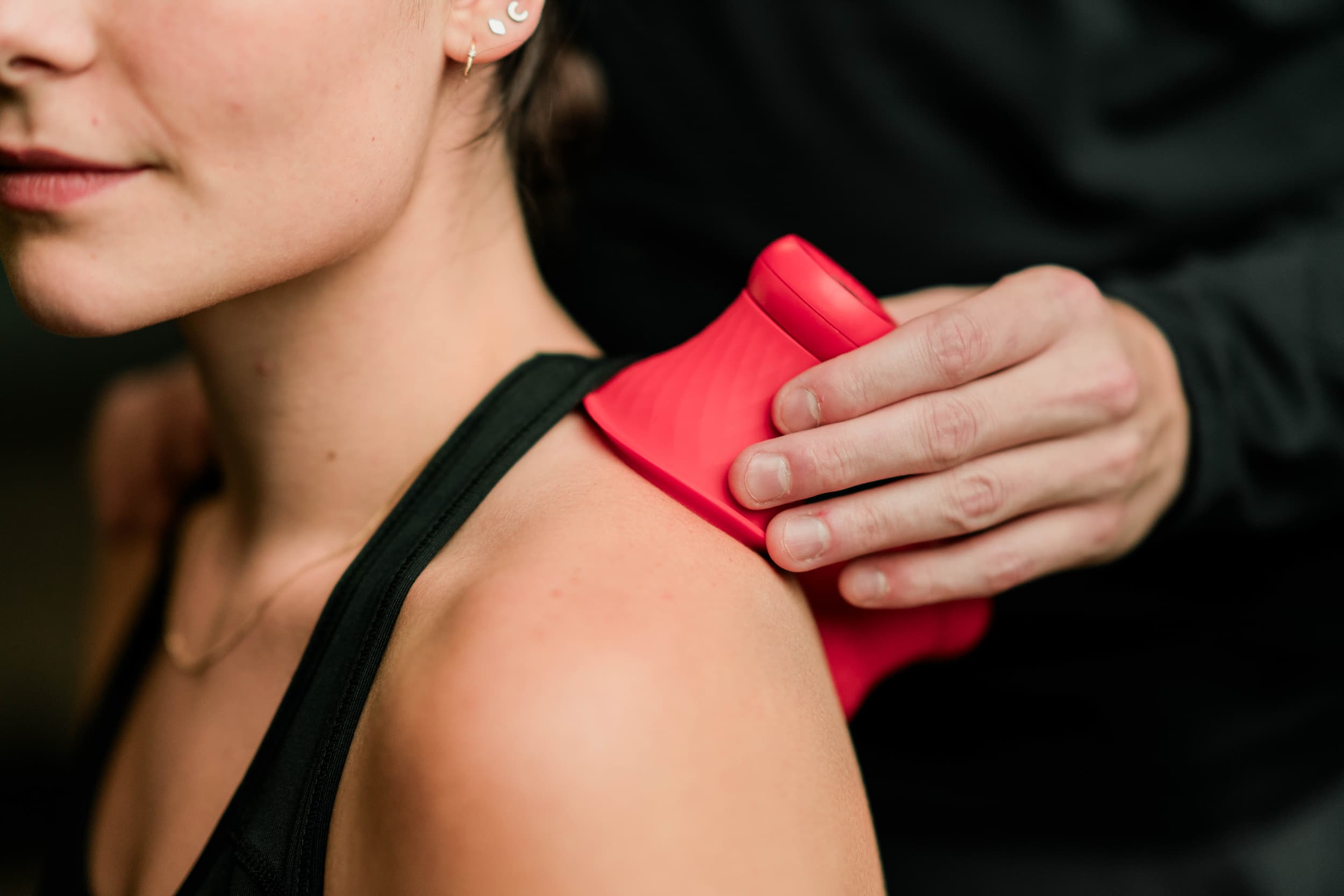 Close up of practitioner applying cupping tool to a patient's shoulder.