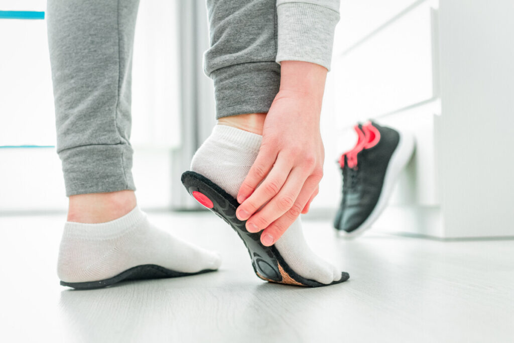 Person in sock pressing an orthotic insert to their foot to test the size before putting into shoes