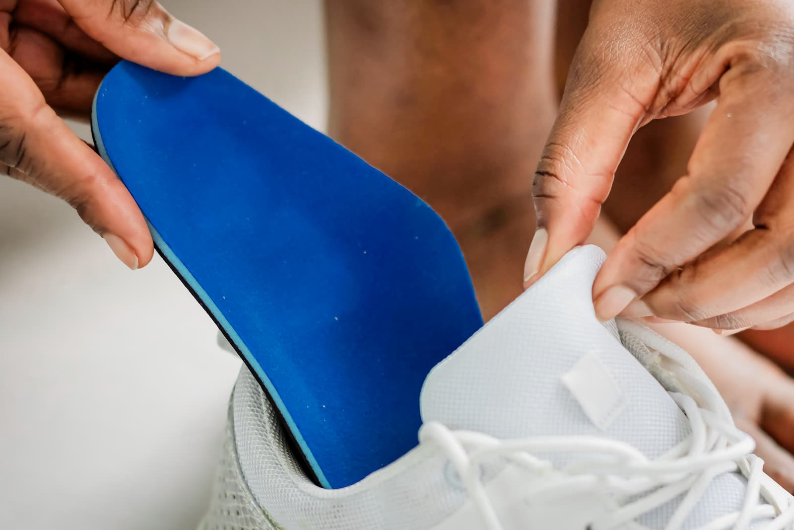 Close up of a blue insert being placed in a white shoe. 