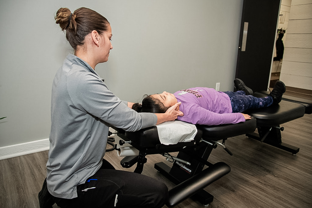 Chiropractor performing a pediatric chiropractic treatment on a young child