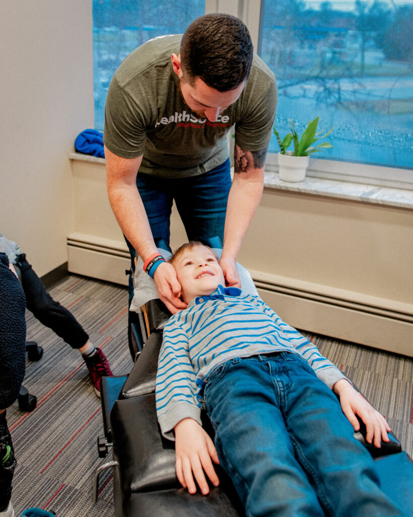 Therapist providing pediatric chiropractic adjustment to school aged child