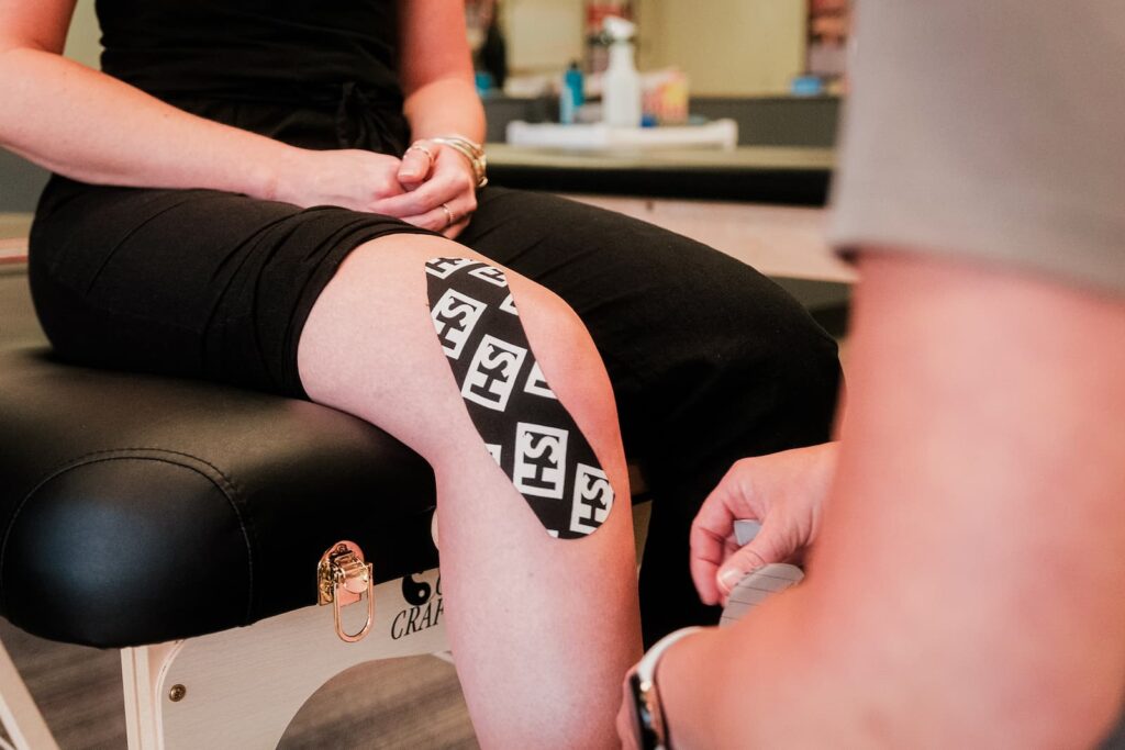 Close up of a patient's knee, wrapped in a single strip of Kinesiology Tape.