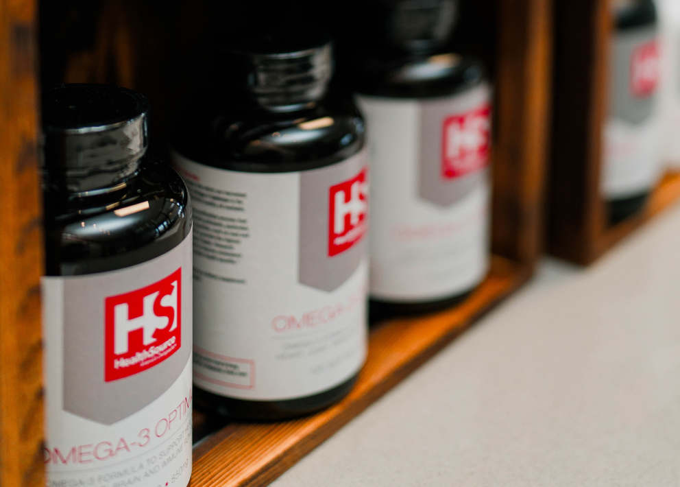 Omega-3 supplement bottles aligned on a wooden wall shelf.