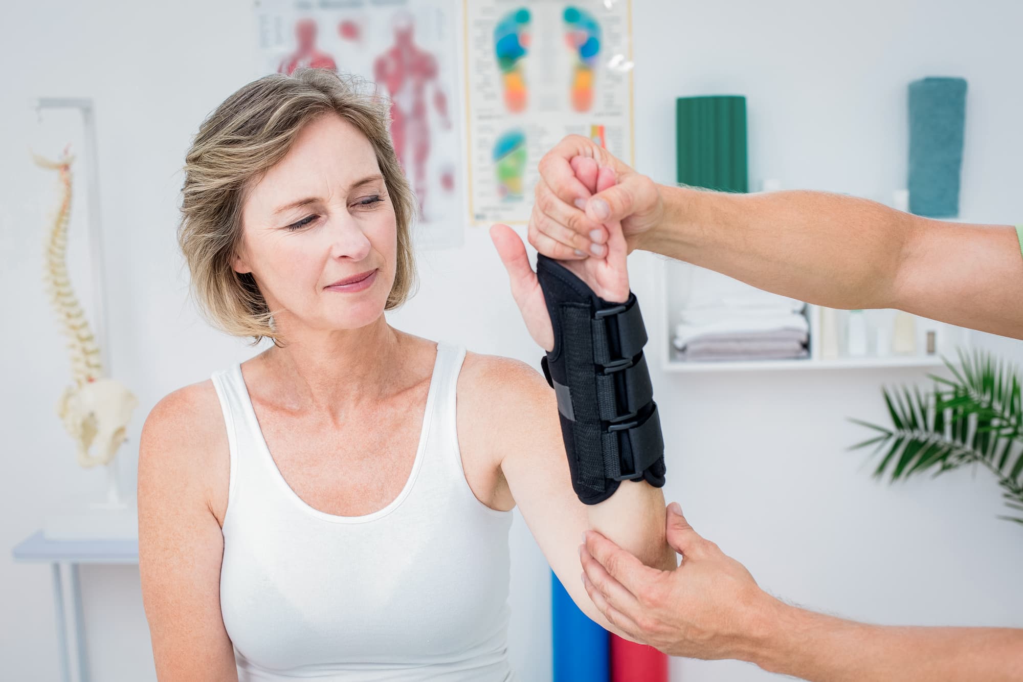 Woman in a healthcare office watches as her wrist is fitted with a wrist guard.