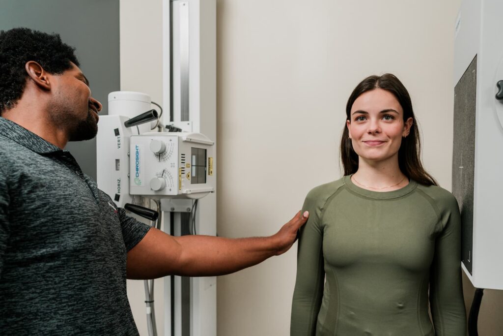 A HealthSource chiropractor helps a patient pose correctly for an x-ray.