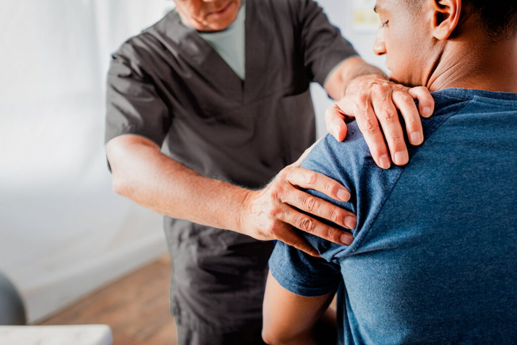 A chiropractor evaluates a patient's shoulder.