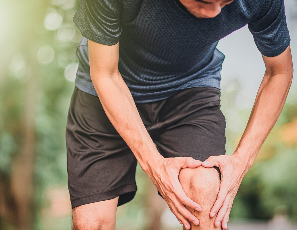 Man holding his knee in pain due to an injury.