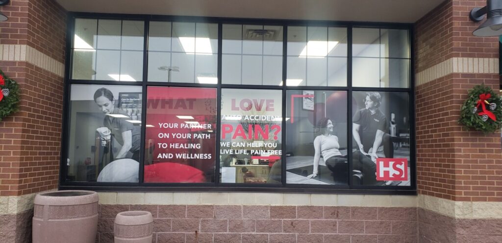 Exterior entrance and window decals outlining services offered at HealthSource of Elk River.