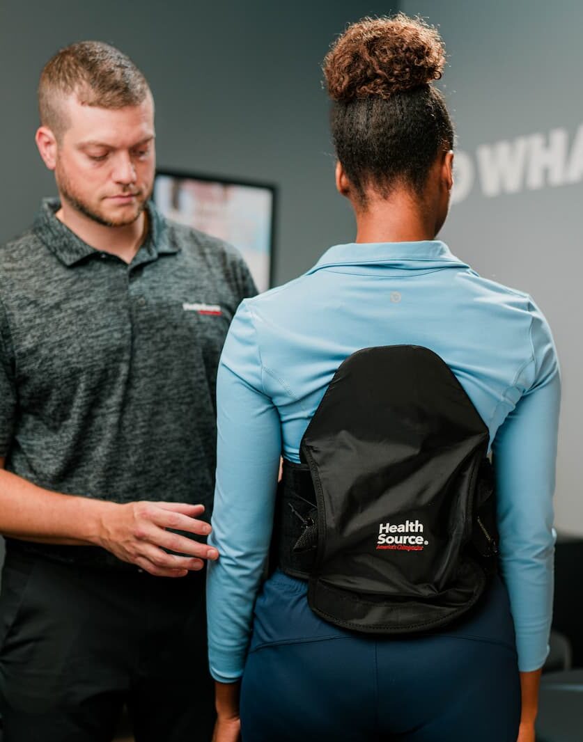 Practitioner adjusts a back brace on a patient.