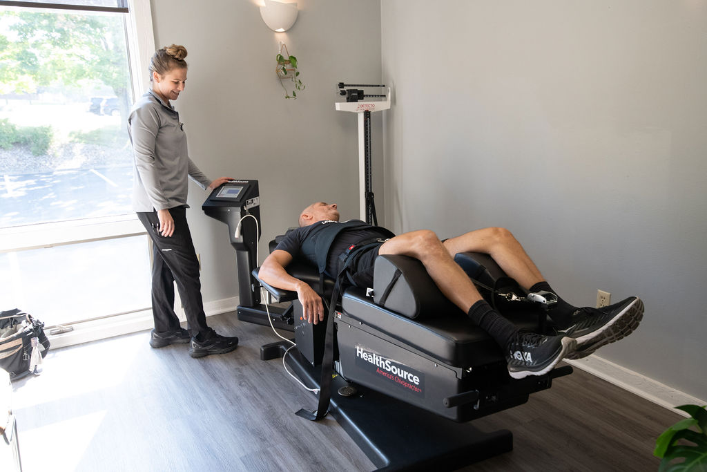 A rehabilitation specialist assisting a chiropractic patient on the spinal decompression table at HealthSource of Boardman