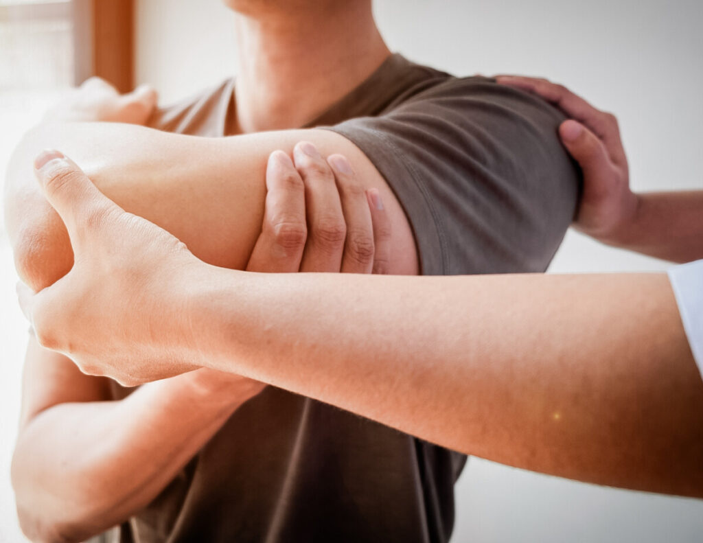 Chiropractor checking the arm of a commercial driver during a DOT Physical.