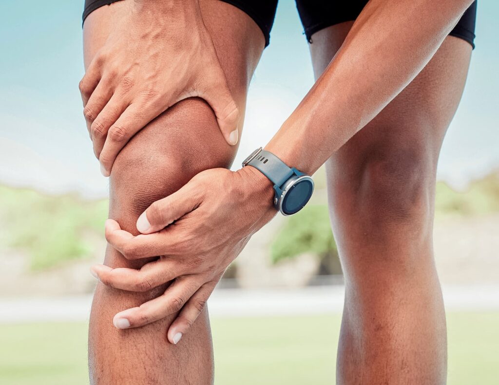 Close up of athlete's legs with hands wrapped around the right knee.