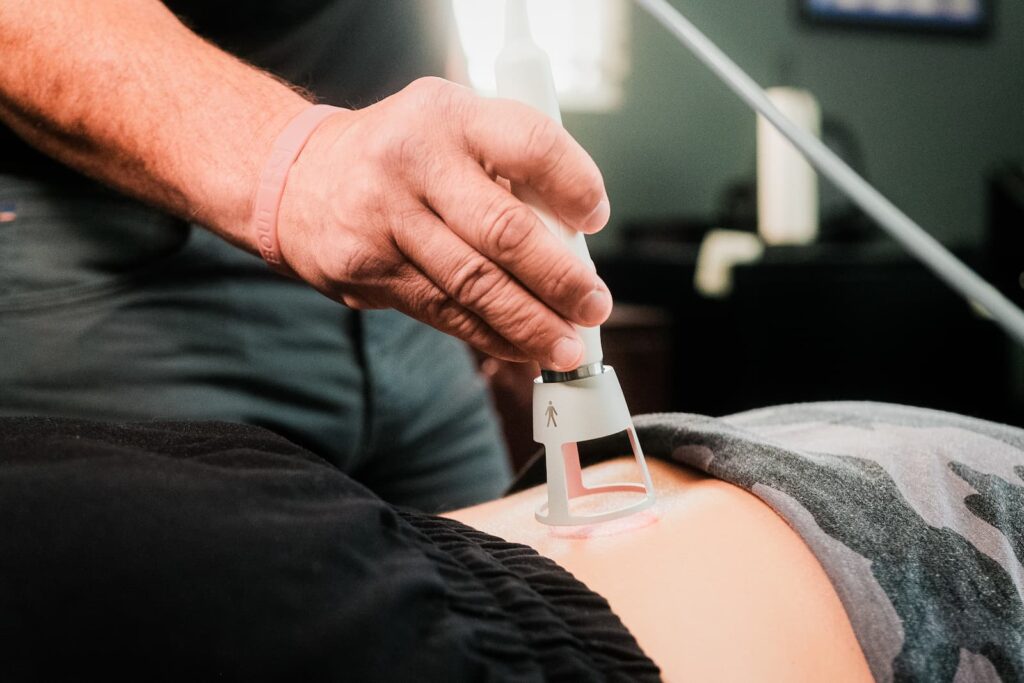 Close up of practitioner applying laser treatment to patient's lower back.