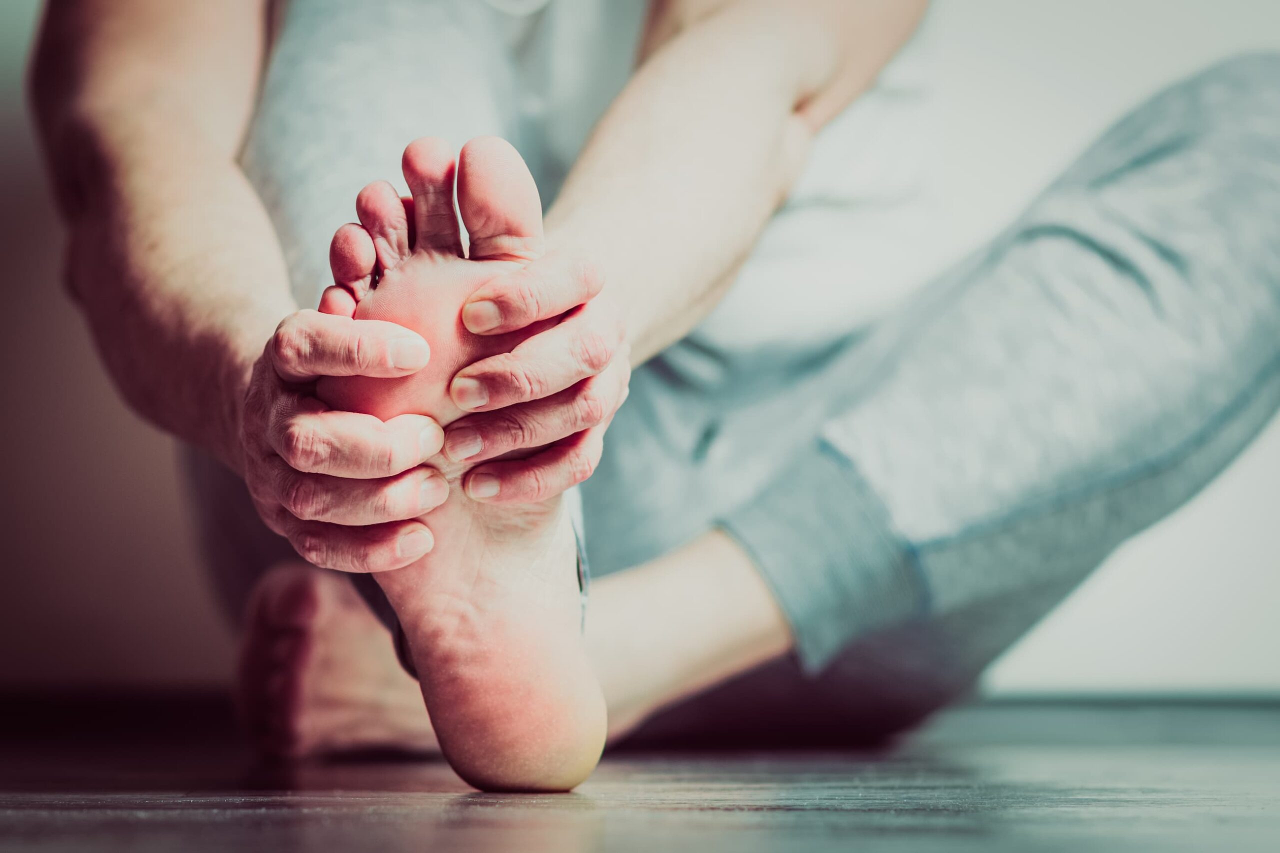 Close up of a person's foot, with their hands wrapped around and gripping in pain.