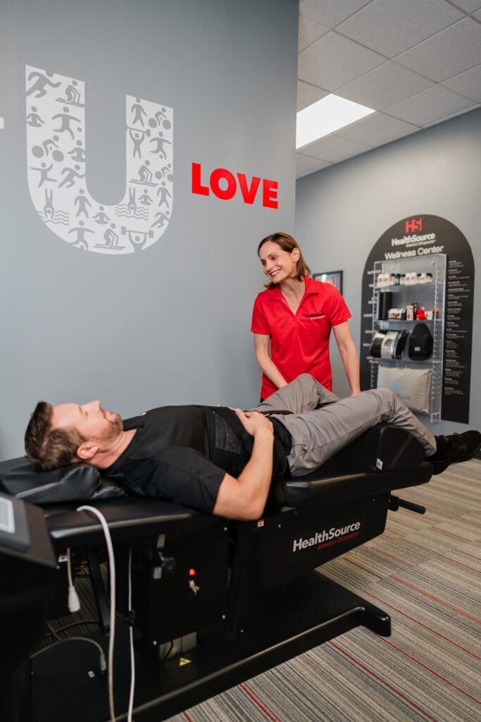 Patient lays on an spinal decompression table as a practitioner adjusts their position.