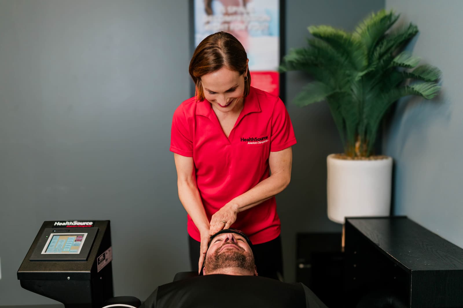 Practitioner adjusts patient's head as they lay on an exam table.