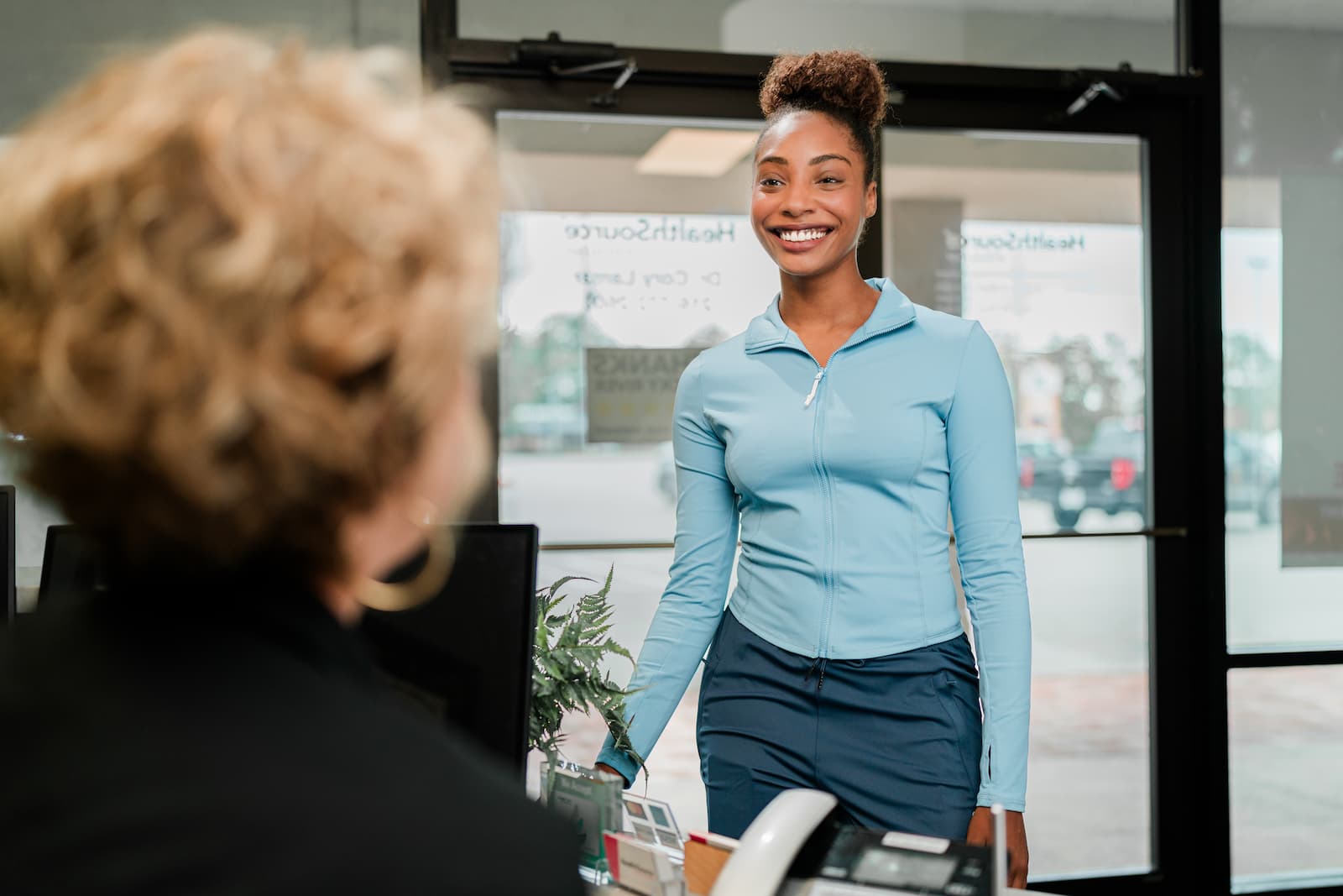 Patient who has just walked in greets a practitioner at the front desk.