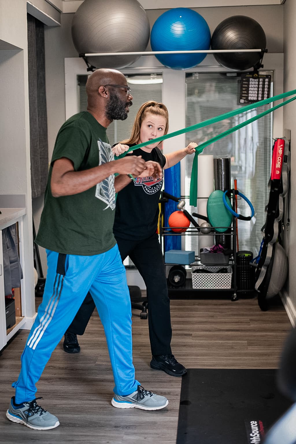 Patient pulls at tension cables as a practitioner helps guide them.