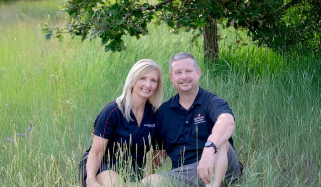 Dr. Chris and Dr. Lisa Holowiski, sitting in the grass. Dr.'s at HealthSource of Denver - DTC.