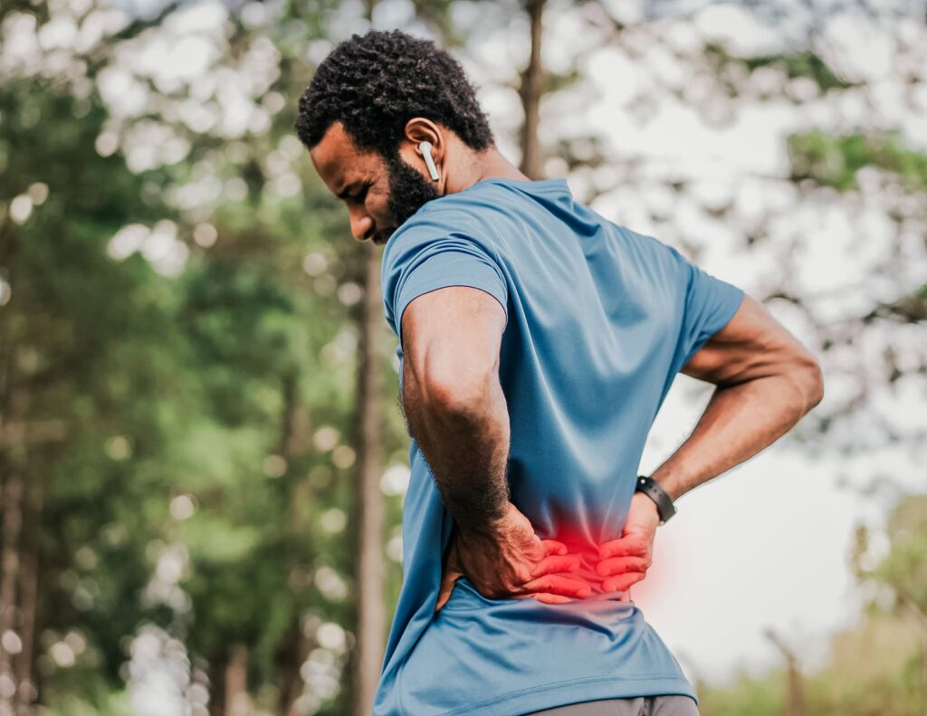 Athlete stops their exercise to press on their lower back, grimacing in pain.