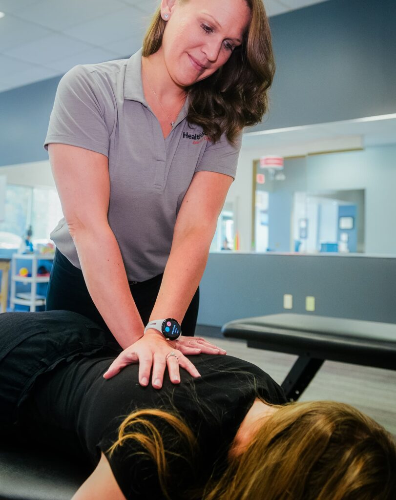 Practitioner presses down on a patient's shoulders.