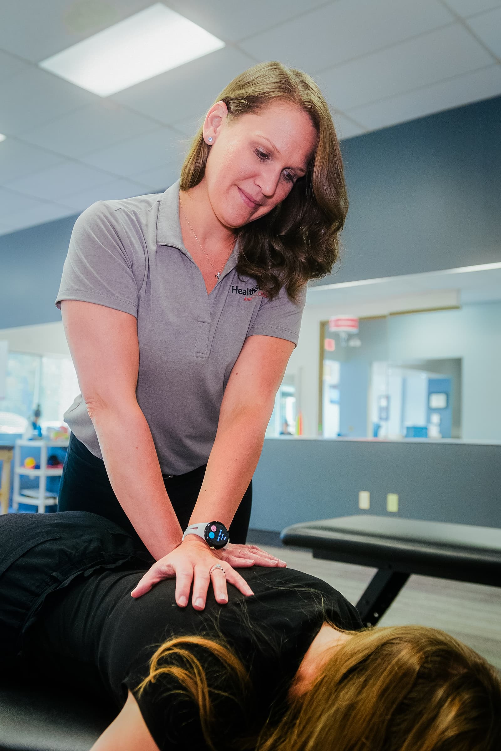 Practitioner presses down on a patient's shoulders.