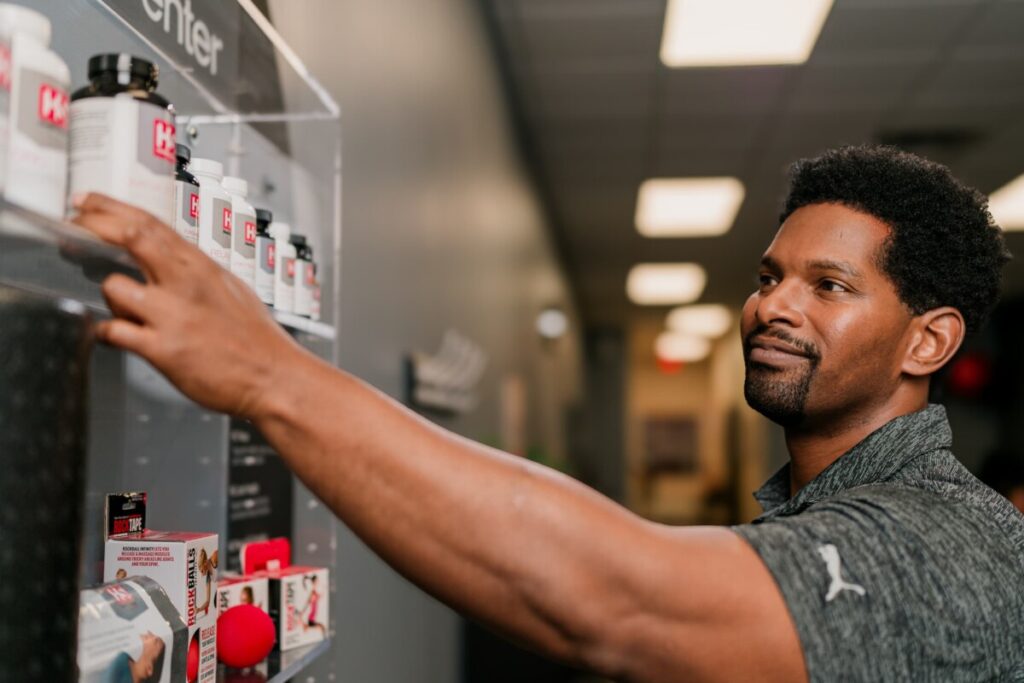 Practitioner standing in front of product display reaches for a far left supplement bottle.