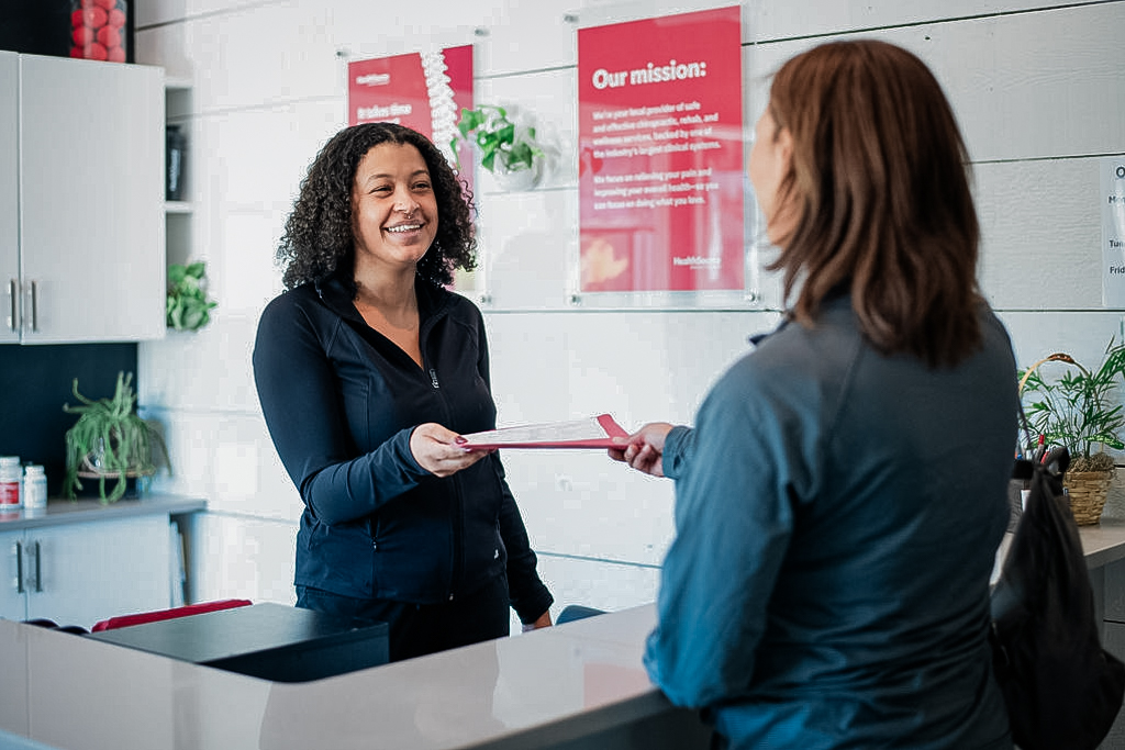 Patient hands documentation to front desk employee.