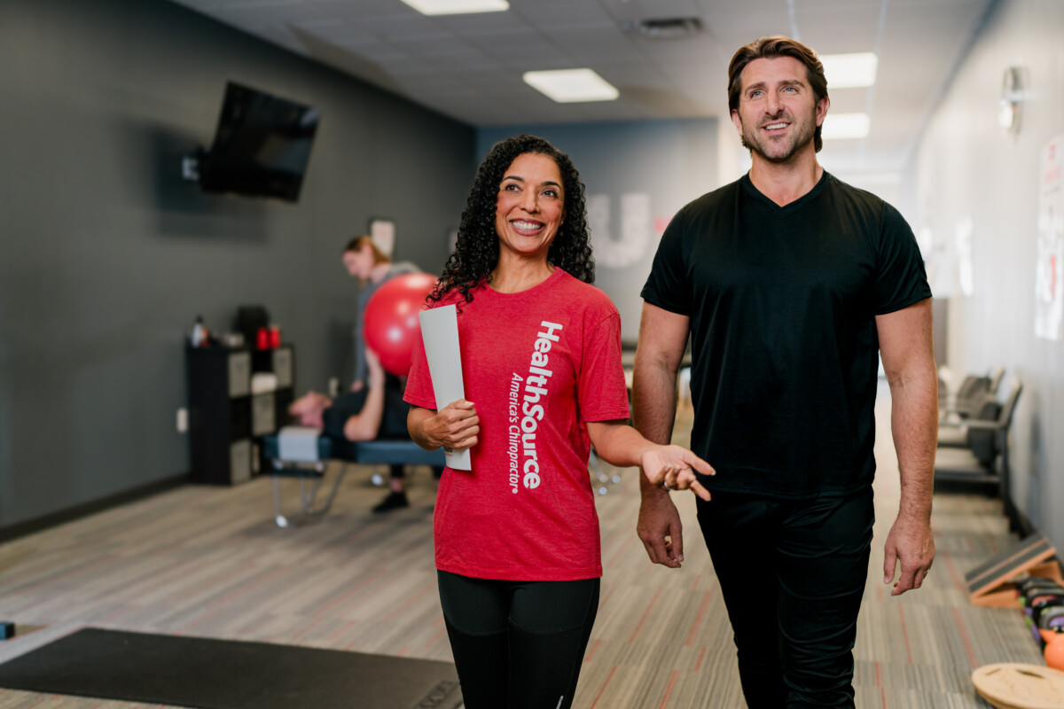 A chiropractic doctor shows a patient through the clinic