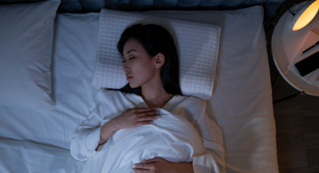 Woman sleeps in bed on a therapeutic pillow