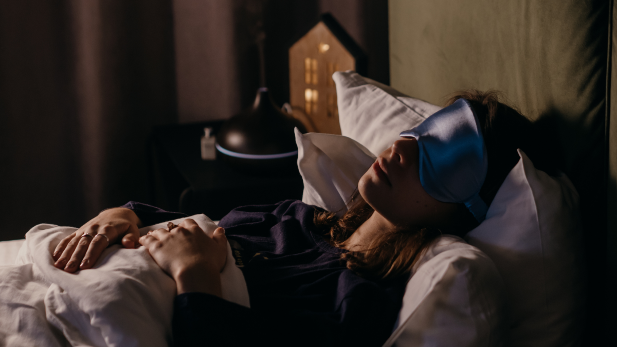 Woman rests in bed with a sleep mask