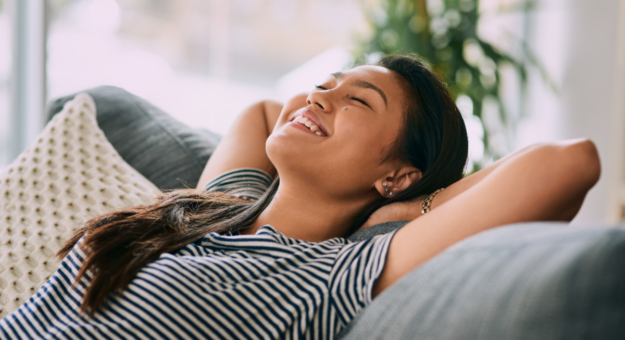 Woman laying back on couch looking relaxed and happy.