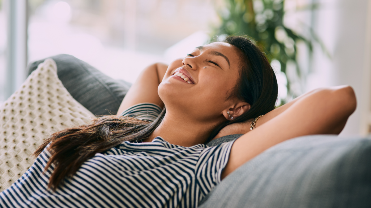 Woman laying back on couch looking relaxed and happy.